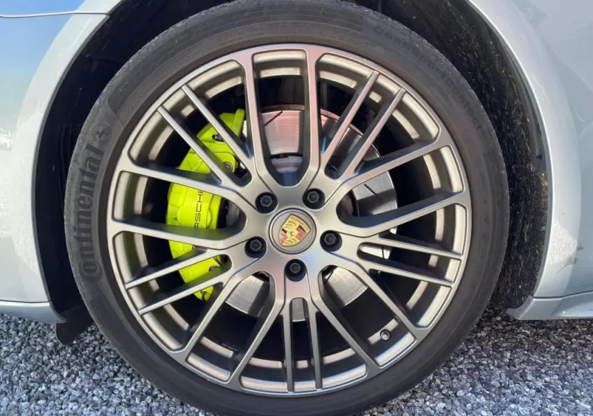 Gros plan sur la roue avant droite grise d'une Porsche Panamera 4 Hybrid avec étrier de frein jaune vif.