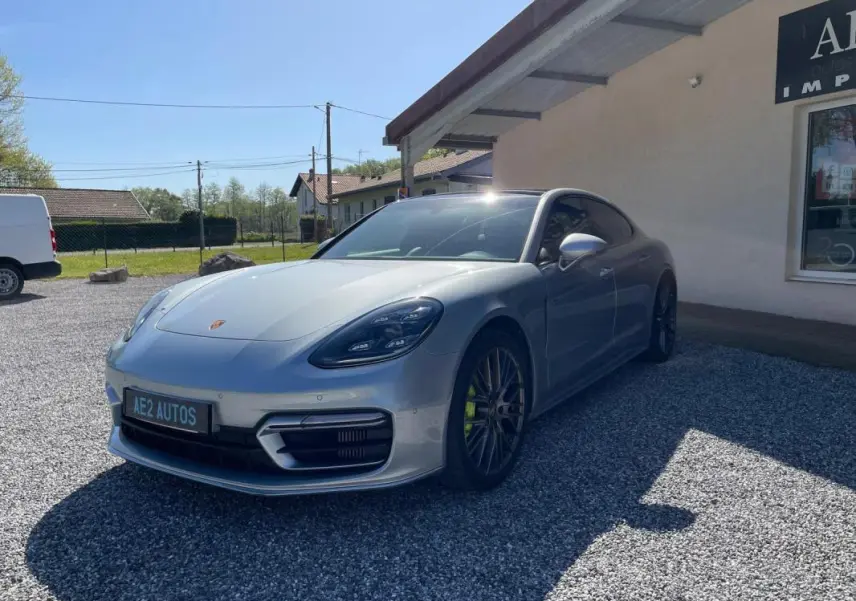 Porsche Panamera 4 V6 Hybrid gris vue 3/4 avant droit, avec jantes noires et étriers de frein verts.