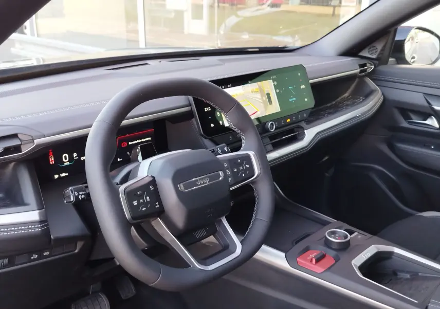 Vue intérieure côté conducteur du Jeep Compass noir Vulcano, avec volant multifonction et écran tactile large.
