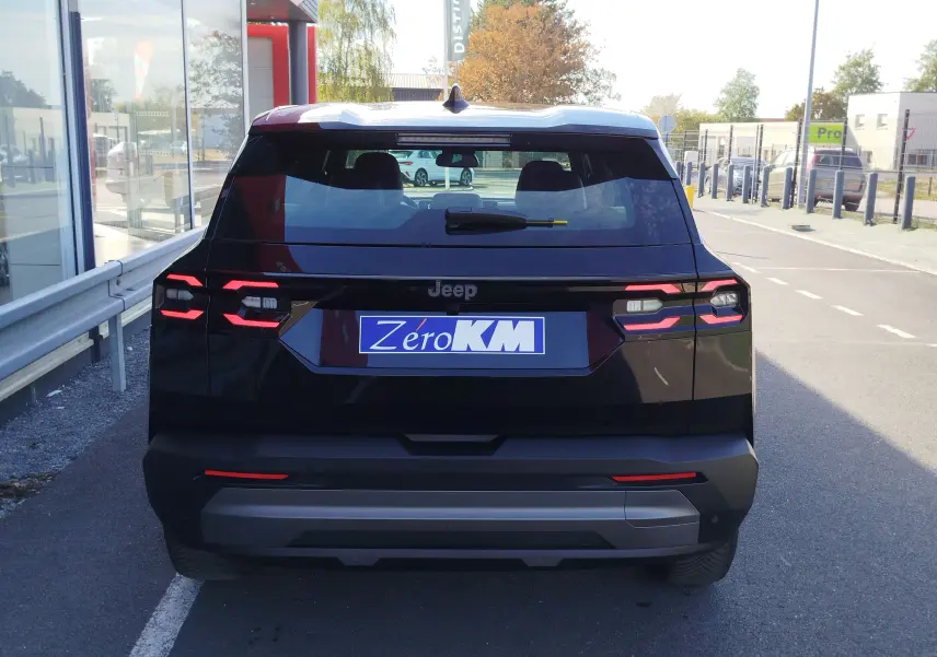 Vue arrière d'un Jeep Compass noir Vulcano métal 2026 avec feux LED distinctifs et plaque Zéro KM visible.
