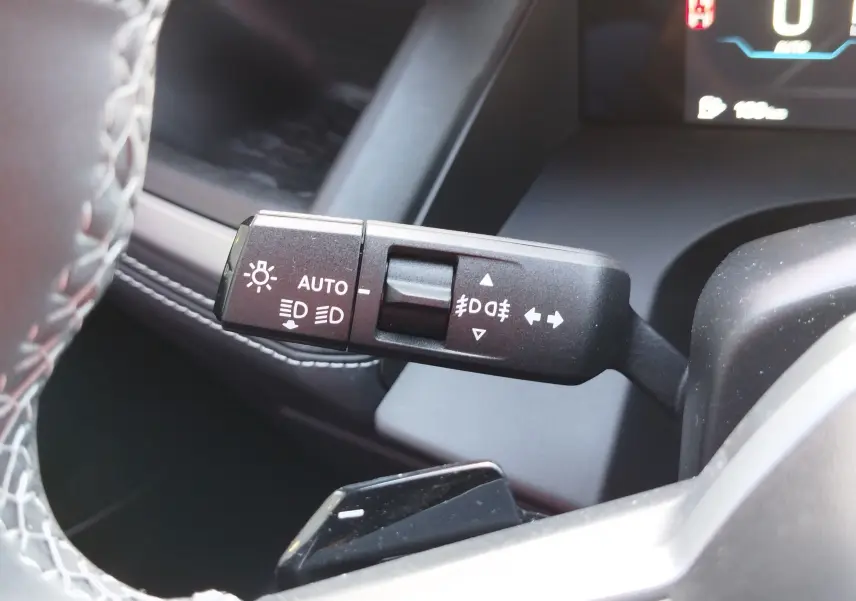 Gros plan sur la commande des feux et clignotants à gauche du volant dans un Jeep Compass noir Vulcano 2026.