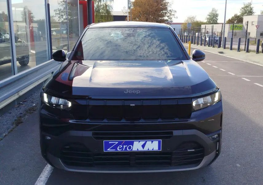 Vue frontale d’un Jeep Compass noir Vulcano métal avec calandre noire et phares LED allumés, stationné en extérieur.