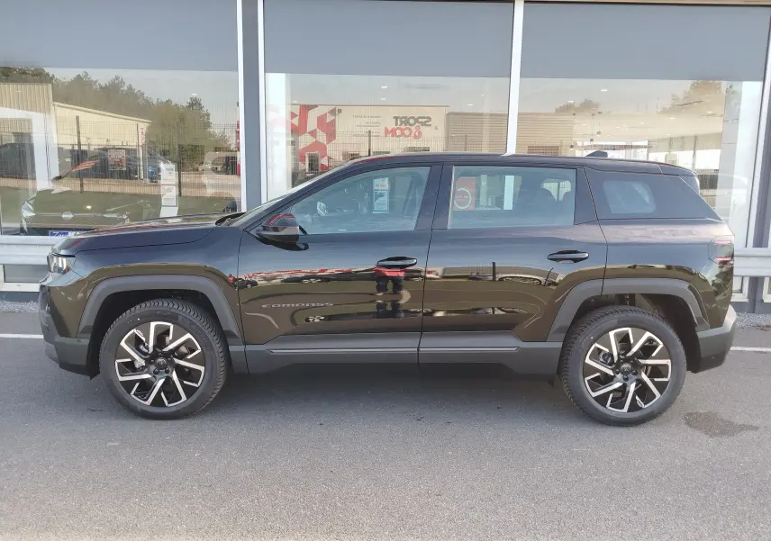 Profil latéral droit du Jeep Compass noir Vulcano métal 2026 avec jantes alliage et protections noires sur les passages de roues.
