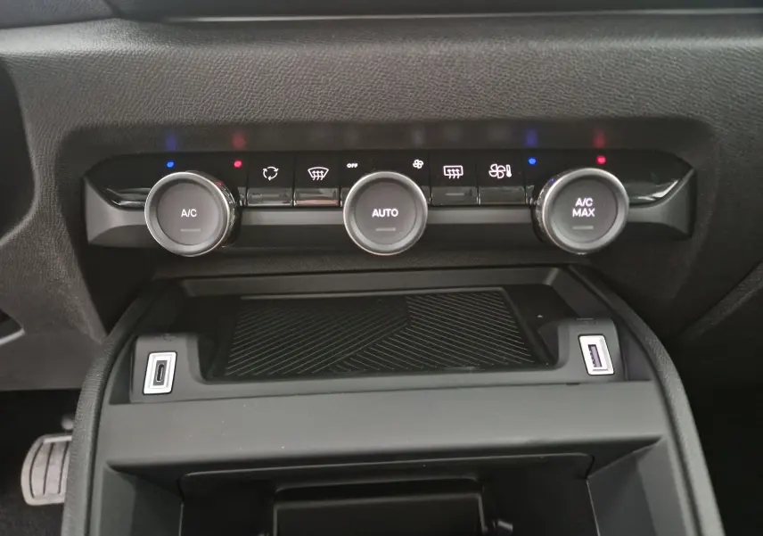 Vue rapprochée de la console centrale noire de la Citroën C4 2025, montrant les commandes de climatisation automatique et deux ports USB.