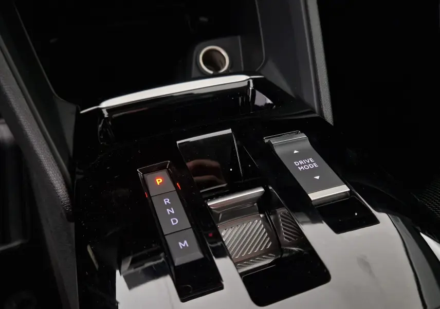 Gros plan sur la console centrale noire brillante de la Citroën C4 1.2 HYBRID 145 e-DSC6 PLUS avec levier de vitesses automatique et bouton Drive Mode.