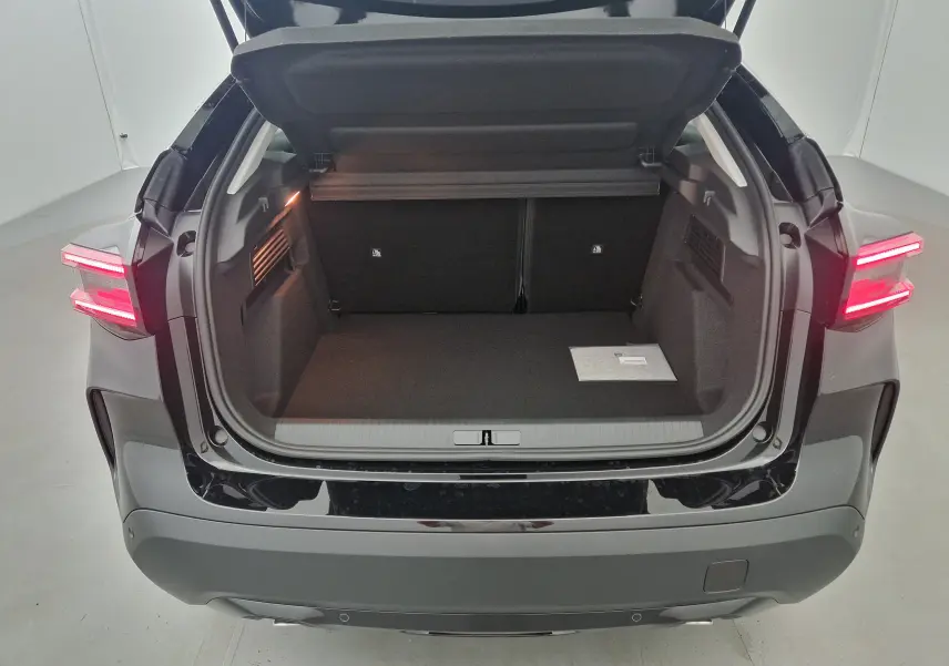 Coffre ouvert vu de l'arrière d'une Citroën C4 noire 2025, avec feux arrière allumés et intérieur spacieux.