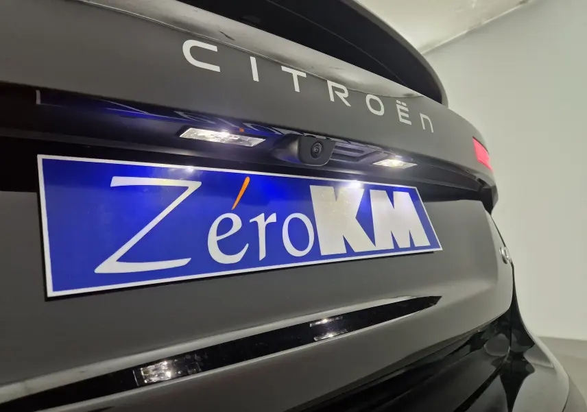 Gros plan sur l'arrière noir brillant d'une Citroën C4 1.2 HYBRID 145 e-DSC6 PLUS avec plaque Zéro KM et caméra de recul.