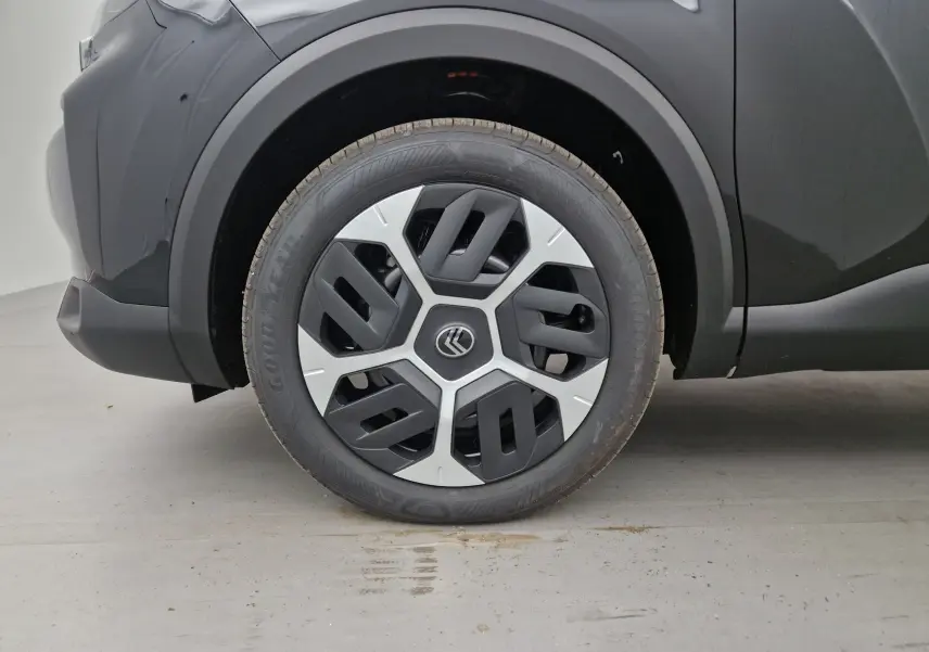 Gros plan sur la roue avant gauche d'une Citroën C4 noire 2025, avec jante au design géométrique bicolore.