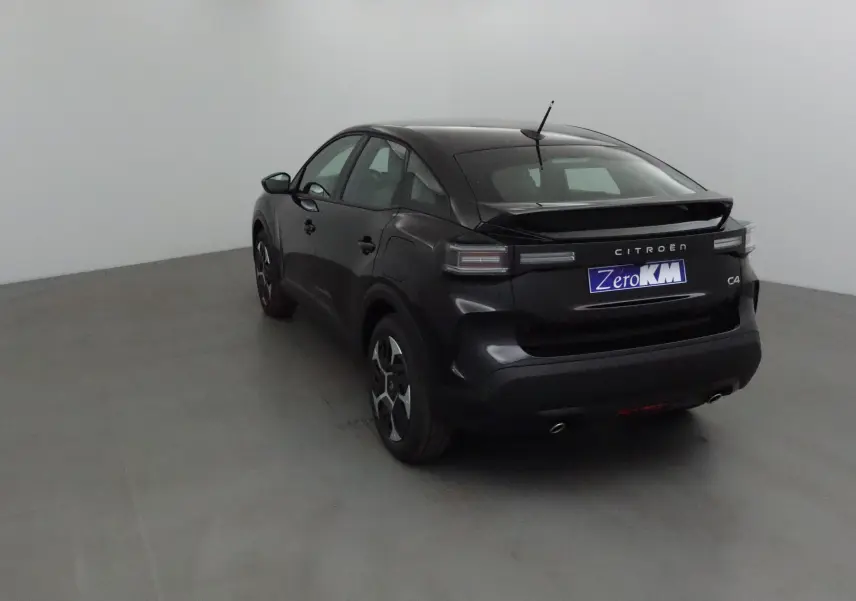 Vue 3/4 arrière gauche d'une Citroën C4 noire 2025 avec feux arrière LED et double sortie d'échappement visible.
