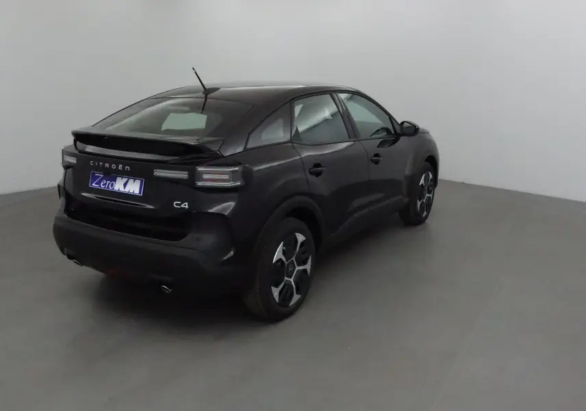 Vue 3/4 arrière droite d'une Citroën C4 noire 2025 avec toit incliné et jantes au design moderne.