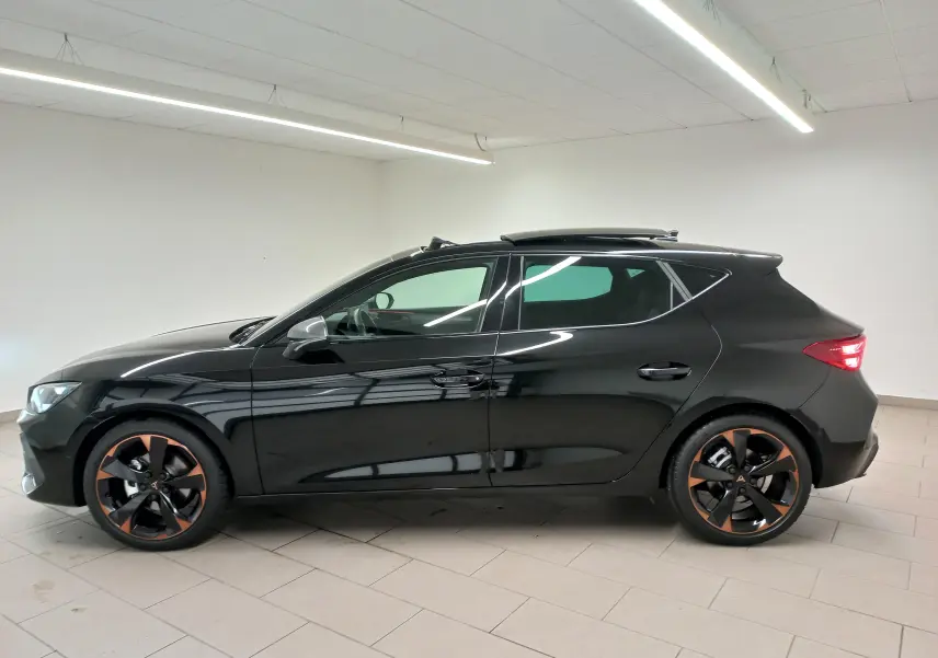 Profil droit d'une CUPRA Leon 2025 noir minuit avec toit ouvrant panoramique et jantes cuivrées 18 pouces en alliage.