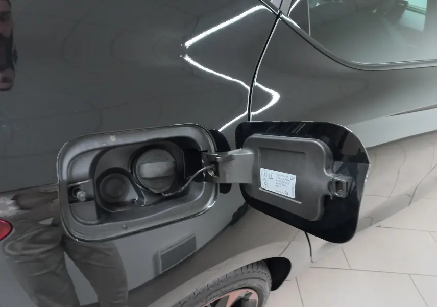 Trappe à carburant ouverte côté gauche sur CUPRA Leon Noir Minuit avec jantes cuivrées visibles en partie arrière.