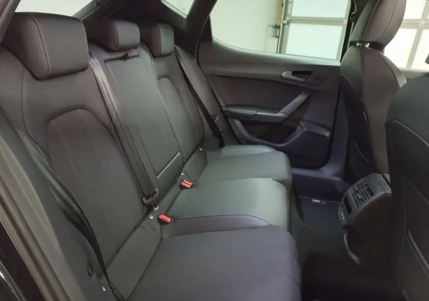 Vue intérieure arrière côté droit des sièges noirs du CUPRA Leon Ph.2 avec ceinture et aérateurs centraux visibles.