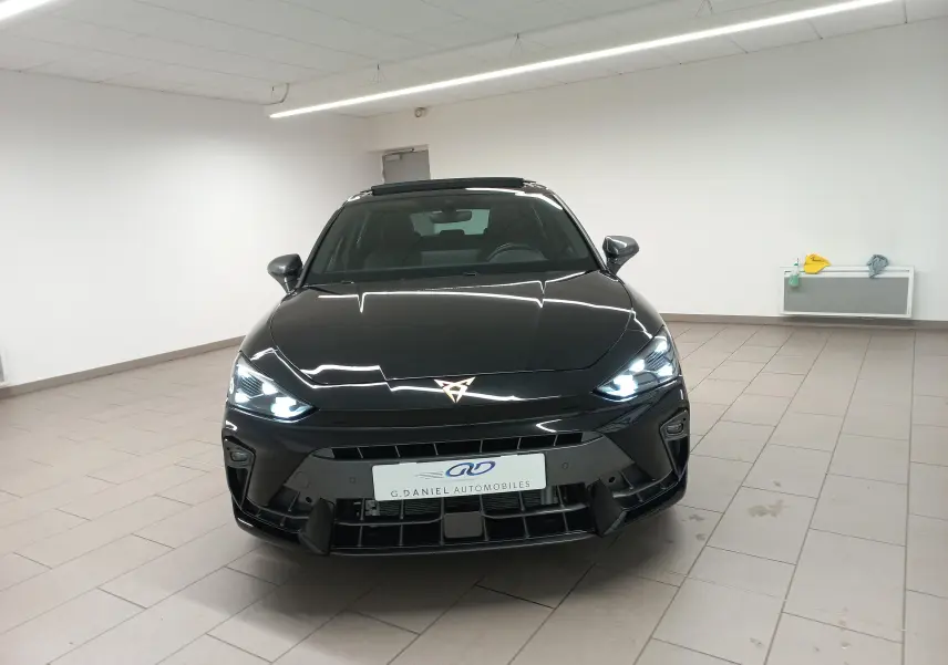 Vue frontale d'une CUPRA Leon 2025 Noir Minuit avec phares allumés et toit ouvrant panoramique visible