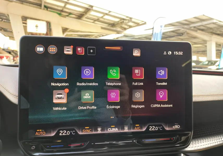 Écran tactile central du CUPRA Leon Ph.2 noir, affichant les menus de navigation et assistance à 15h32 dans un intérieur lumineux.