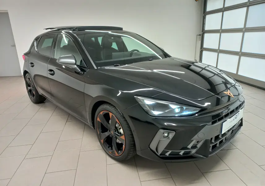 Vue 3/4 avant gauche d'une CUPRA Leon 2025 noir minuit avec jantes cuivrées et toit ouvrant panoramique visible.