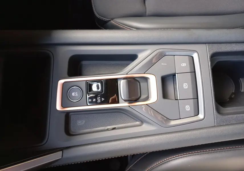 Vue rapprochée de la console centrale noire avec levier de vitesses électronique et surpiqûres cuivrées du CUPRA Leon 2025.