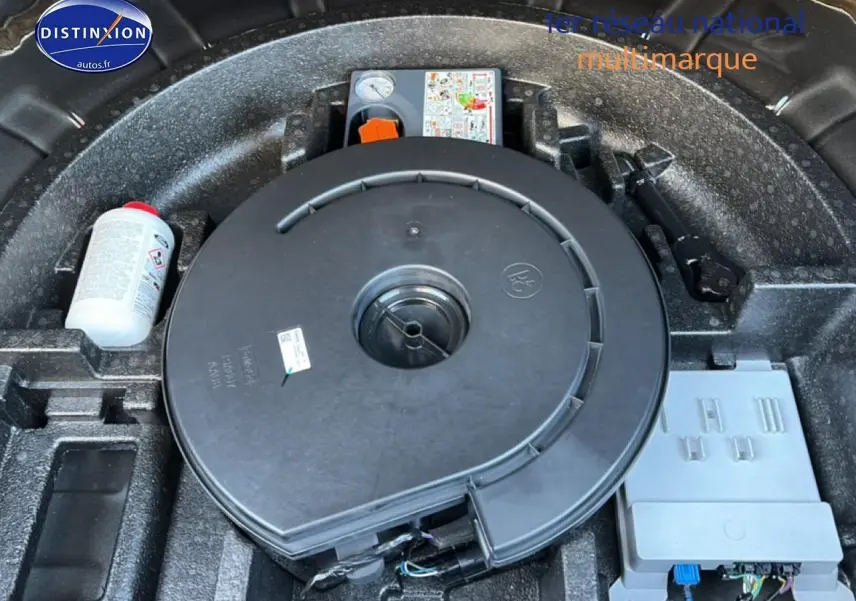 Vue rapprochée du compartiment de roue de secours d'une Ford Focus noire 2024, montrant le kit de réparation et les outils intégrés.