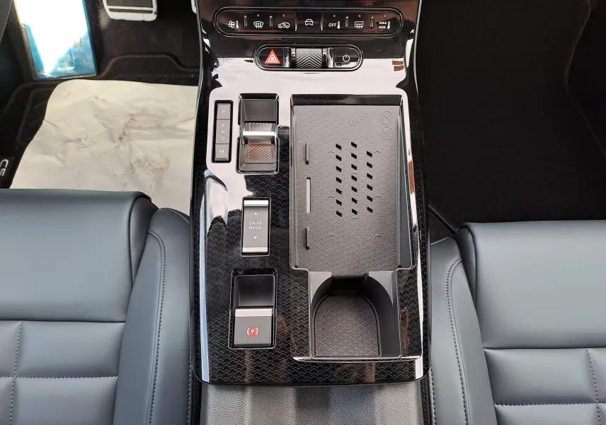 Vue plongeante sur la console centrale noire brillante du Citroën C5 Aircross hybride, avec commandes de boîte auto et porte-gobelet.