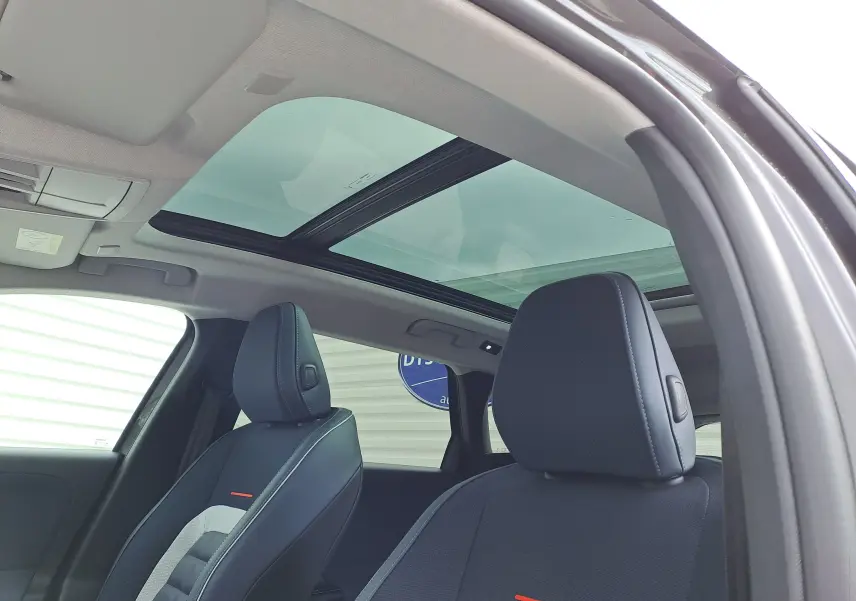 Vue intérieure du Citroën C5 Aircross hybride 2026, sièges avant gris noir avec toit panoramique en verre.