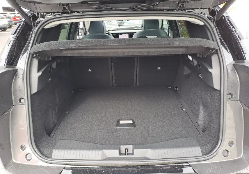 Coffre ouvert vu de l'arrière d'un Citroën C5 Aircross gris platinium avec intérieur noir et tablette cache-bagages.