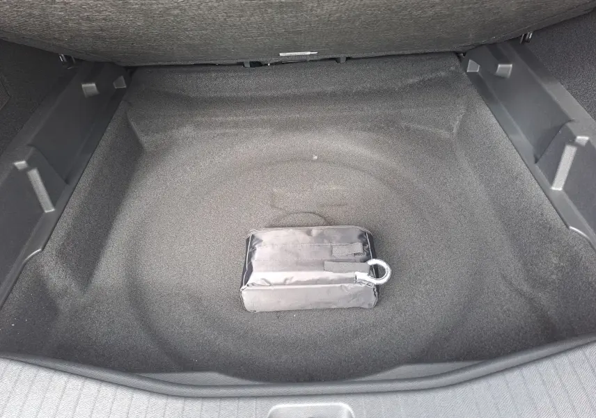 Vue intérieure du coffre vide gris platinium du Citroën C5 Aircross 2026 avec un kit de secours noir posé au centre.
