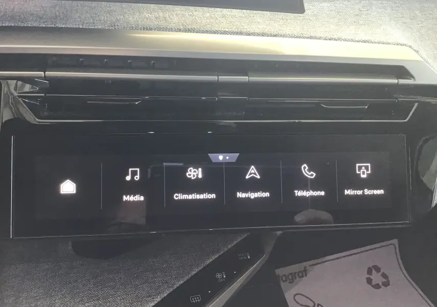 Gros plan sur les commandes de climatisation du Peugeot 3008 gris titane, avec boutons tactiles rétroéclairés et tissu gris en arrière-plan.