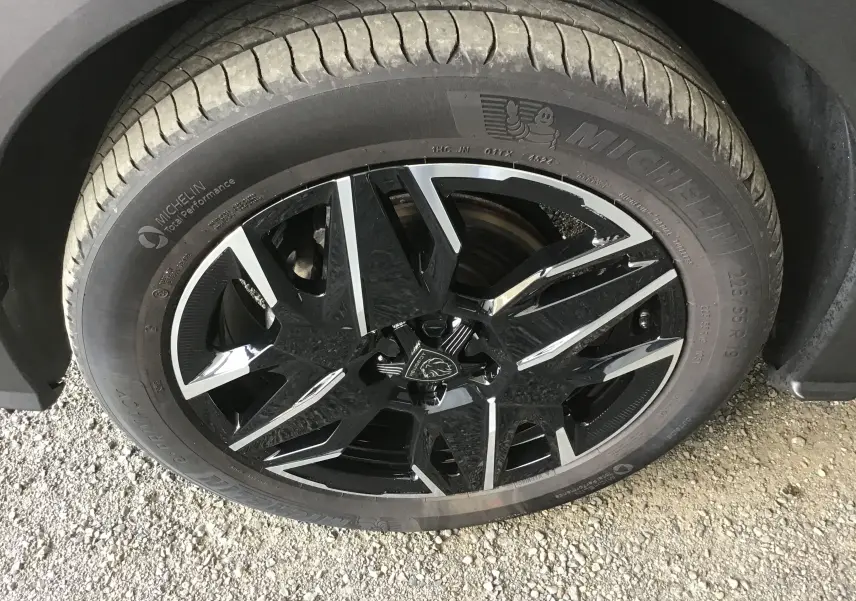 Vue plongeante sur le rangement central ouvert du Peugeot 3008 1.2 HYBRID 145 gris titane, intérieur noir avec surpiqûres claires.