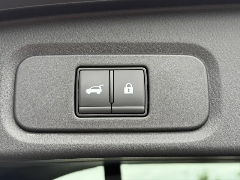 Boutons de commande du hayon et verrouillage intérieur sur un Nissan Qashqai 2025, vue rapprochée du panneau gris.