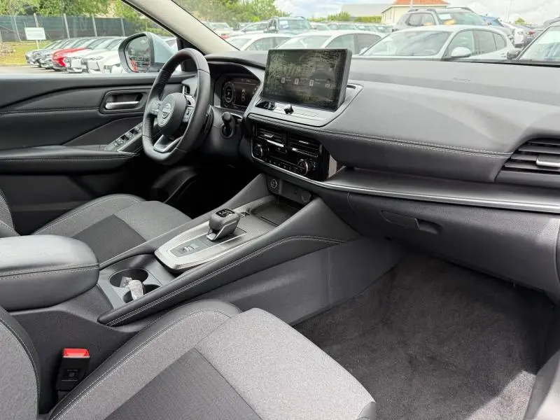 Intérieur avant droit du Nissan Qashqai 2025 gris Argile, avec écran tactile et volant multifonction cuir.