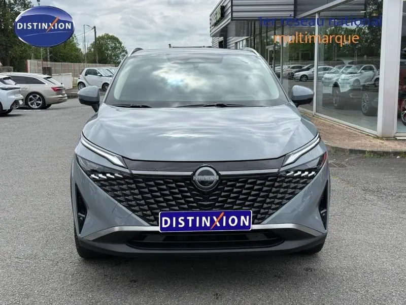 Vue avant frontale du Nissan Qashqai gris Argile avec calandre noire texturée et phares LED fins.