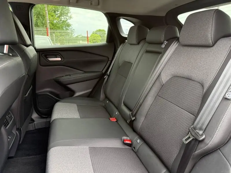 Vue intérieure des sièges arrière du Nissan Qashqai 2025, tissu mixte noir avec ceintures grises et appuie-têtes intégrés.