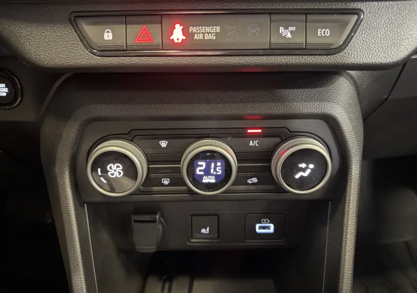 Tableau de bord du Dacia Jogger Hybrid 140 Extreme 2023 montrant les commandes de climatisation et voyants de sécurité allumés.