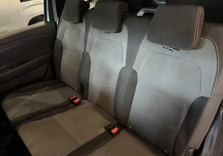 Vue intérieure des sièges arrière noirs et gris du Dacia Jogger Hybrid 140 Extreme, avec appuie-têtes et ceintures visibles.