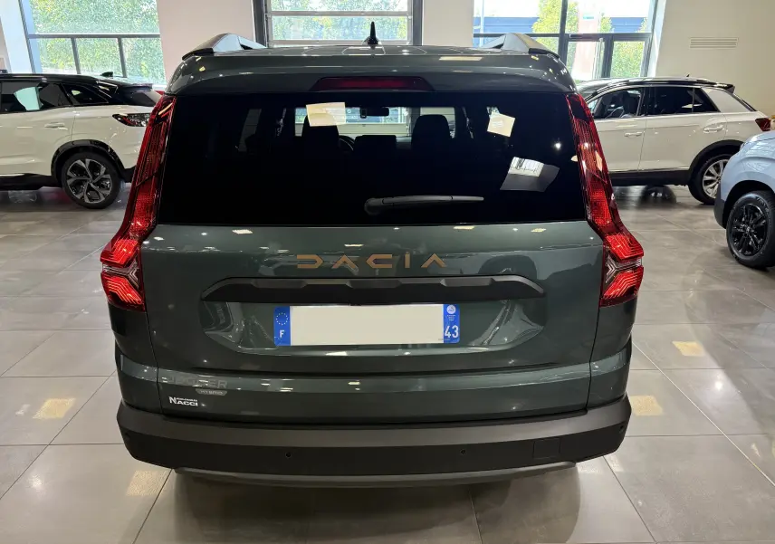 Vue arrière du Dacia Jogger Hybrid 140 Extreme en Vert Cèdre, avec feux arrière verticaux et logo doré visible.