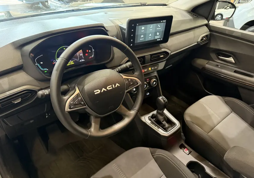Vue intérieure du tableau de bord et volant DACIA Jogger Hybrid 140 Extreme, avec écran tactile et sièges gris.
