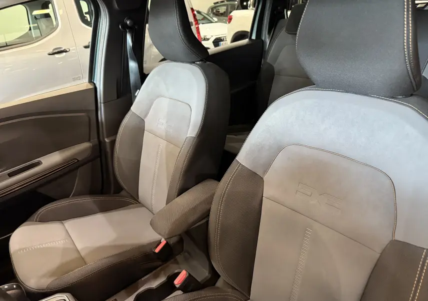 Gros plan sur les sièges avant gris et noirs du Dacia Jogger Hybrid 140 Extreme, avec accoudoir central visible.