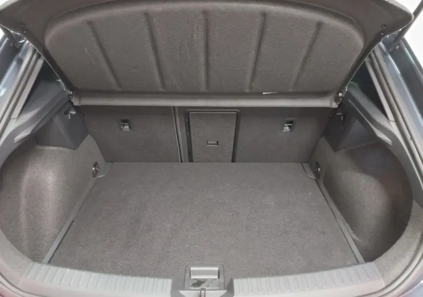 Coffre ouvert vu de l'arrière d'une CUPRA Leon Ph.2 gris magnétique, montrant l'espace de chargement vide et la moquette intérieure.
