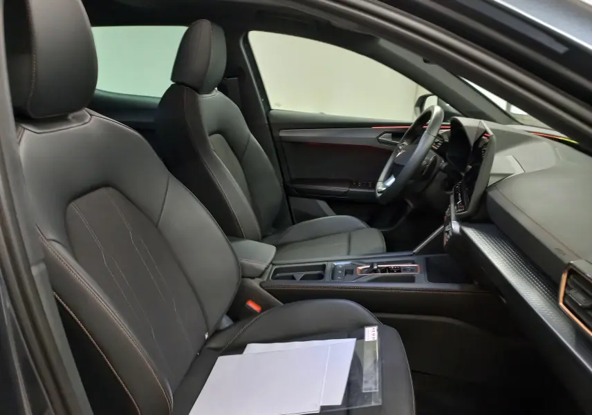 Vue intérieure côté conducteur de la CUPRA Leon 2025 avec sièges noirs et détails cuivrés sur la console centrale.