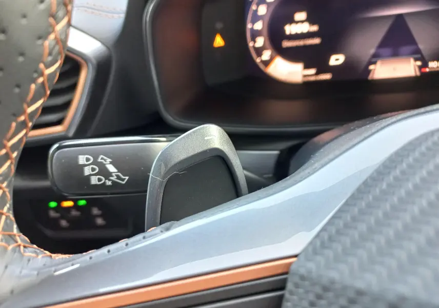 Gros plan sur la commande des feux et palette de changement de vitesse dans l'habitacle du CUPRA Leon gris métallique.