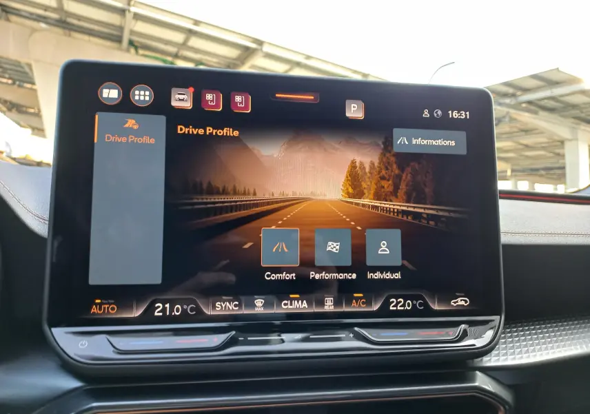 Écran tactile central de la CUPRA Leon 2025 affichant les modes de conduite avec finition intérieure noire et surpiqûres cuivrées.