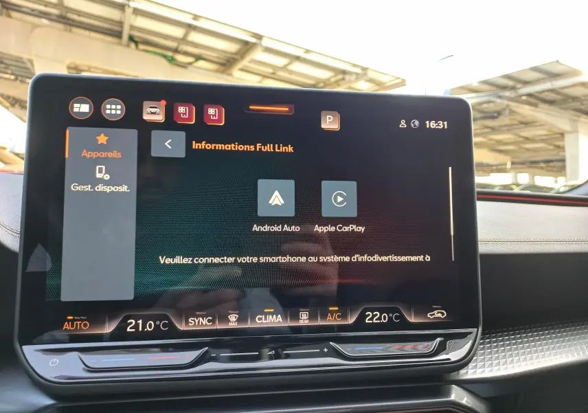 Écran tactile central du tableau de bord d'une CUPRA Leon 2025 affichant les options Android Auto et Apple CarPlay, avec commandes climatisation visibles.