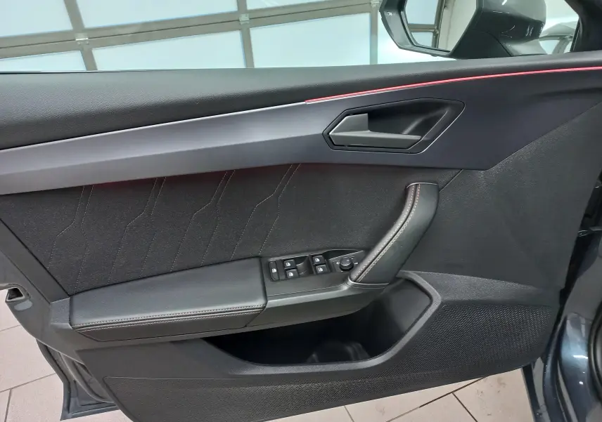 Gros plan sur la porte avant gauche de la CUPRA Leon 2025, avec garniture noire et surpiqûres cuivrées.