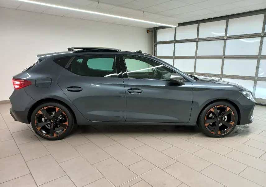 Profil droit de la CUPRA Leon 2025 gris magnétique avec toit ouvrant panoramique et jantes alliage 18'' cuivrées.