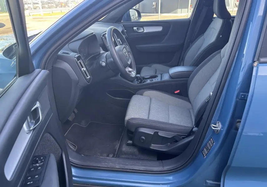 Intérieur avant côté conducteur du Volvo XC40 Fjord Blue 2024 avec sièges gris et tableau de bord moderne.