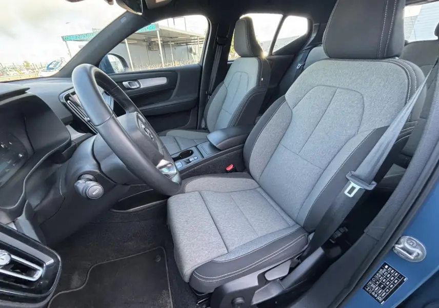 Intérieur avant droit du Volvo XC40 Fjord Blue, sièges tissu gris clair avec volant cuir noir visible.