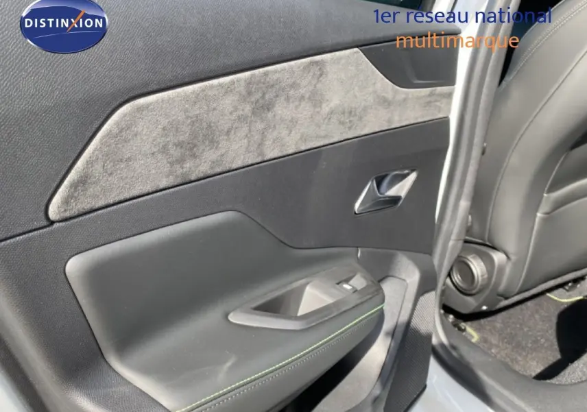 Vue rapprochée de la porte arrière droite de la Peugeot 308 Hybrid 145ch GT blanche, avec insert en tissu gris et surpiqûres vertes.