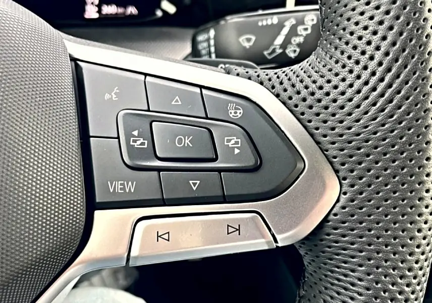 Gros plan sur les commandes multifonctions gauche du volant perforé noir de la Volkswagen Golf 2026 finition R-Line.
