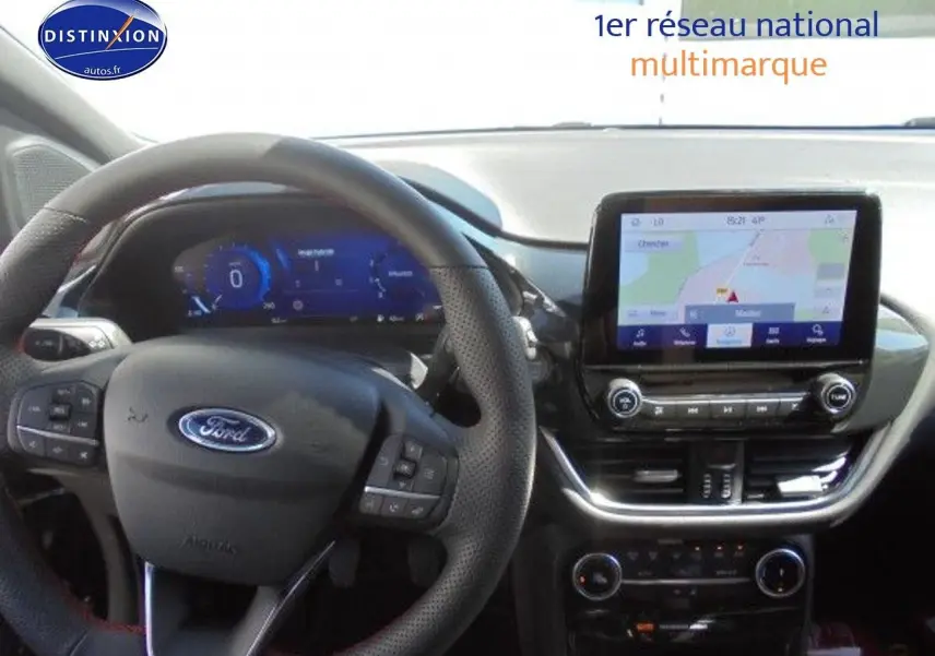 Vue intérieure du tableau de bord et volant noir perforé d'une Ford Puma 2022 avec écran tactile affichant la navigation GPS.