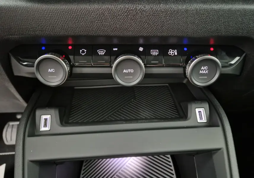Gros plan sur la console centrale du Citroën C4 2025 noir, montrant les commandes de climatisation automatique et deux ports USB.